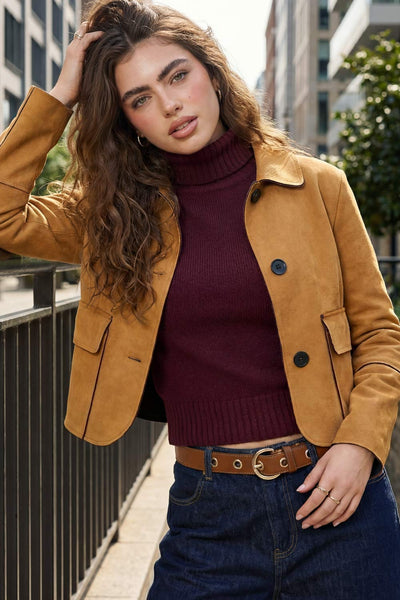 Chamarra corta de fit recto, manga larga con cortes decorativos, cuello camisero con detalle curveado, bolsillos frontales con cartera y cierre frontal con hilera de botones en contraste.