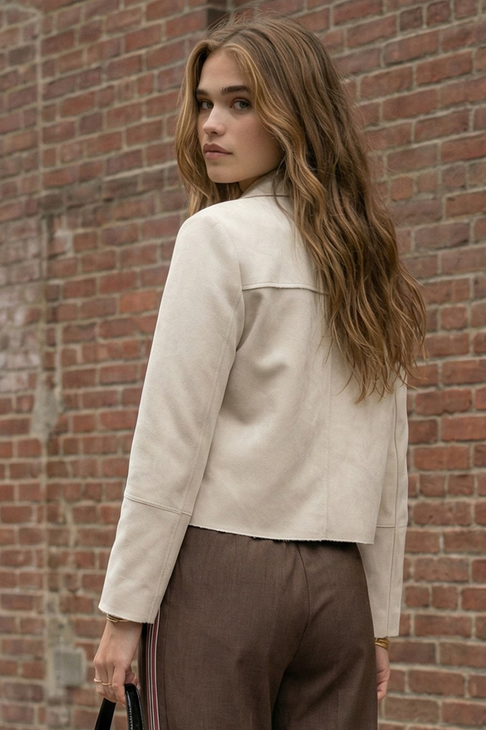 Chamarra corta de fit recto, manga larga con cortes decorativos, cuello camisero con detalle curveado, bolsillos frontales con cartera y cierre frontal con hilera de botones en contraste.