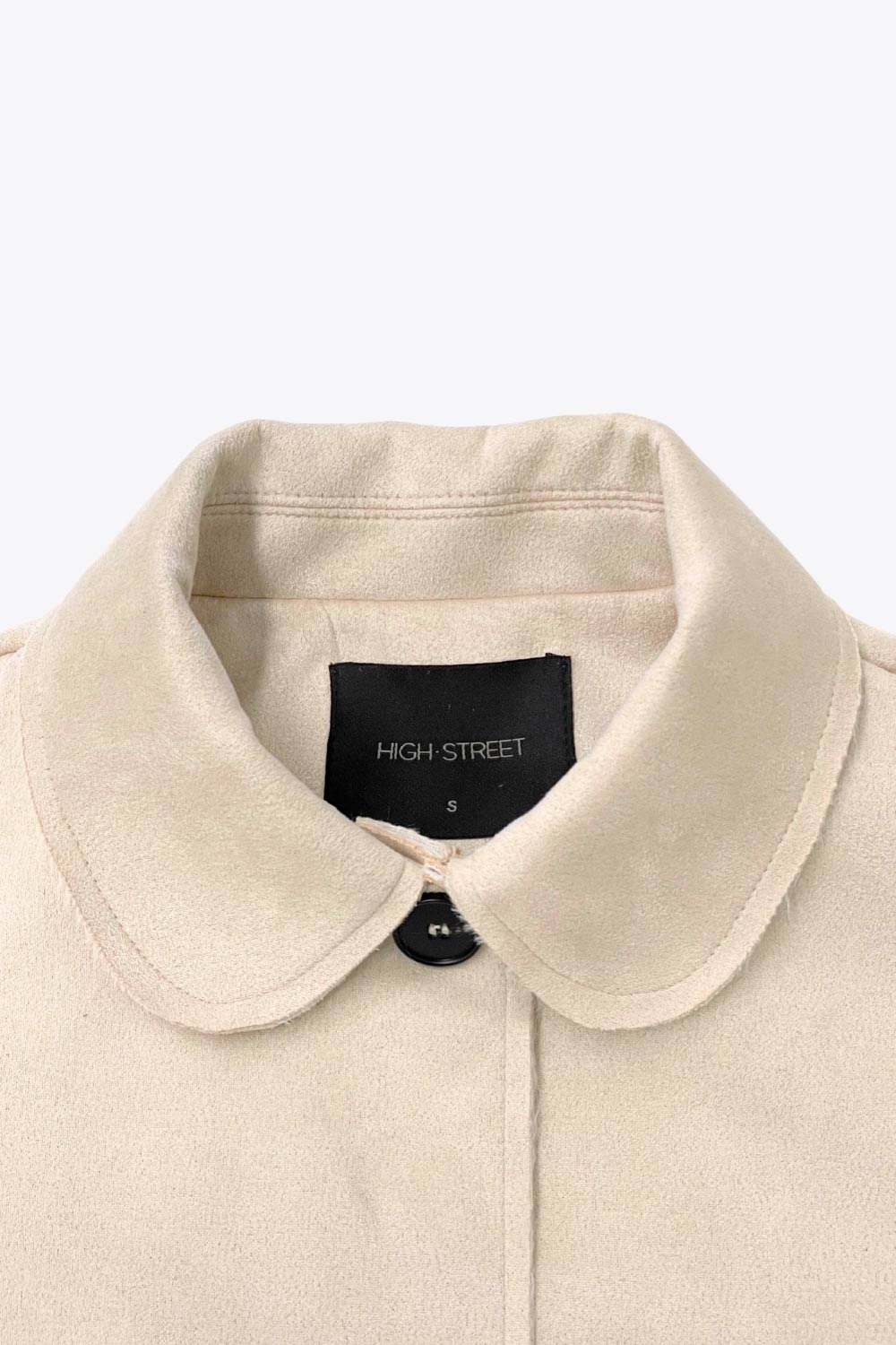 Chamarra corta de fit recto, manga larga con cortes decorativos, cuello camisero con detalle curveado, bolsillos frontales con cartera y cierre frontal con hilera de botones en contraste.