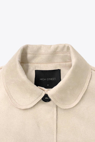 Chamarra corta de fit recto, manga larga con cortes decorativos, cuello camisero con detalle curveado, bolsillos frontales con cartera y cierre frontal con hilera de botones en contraste.