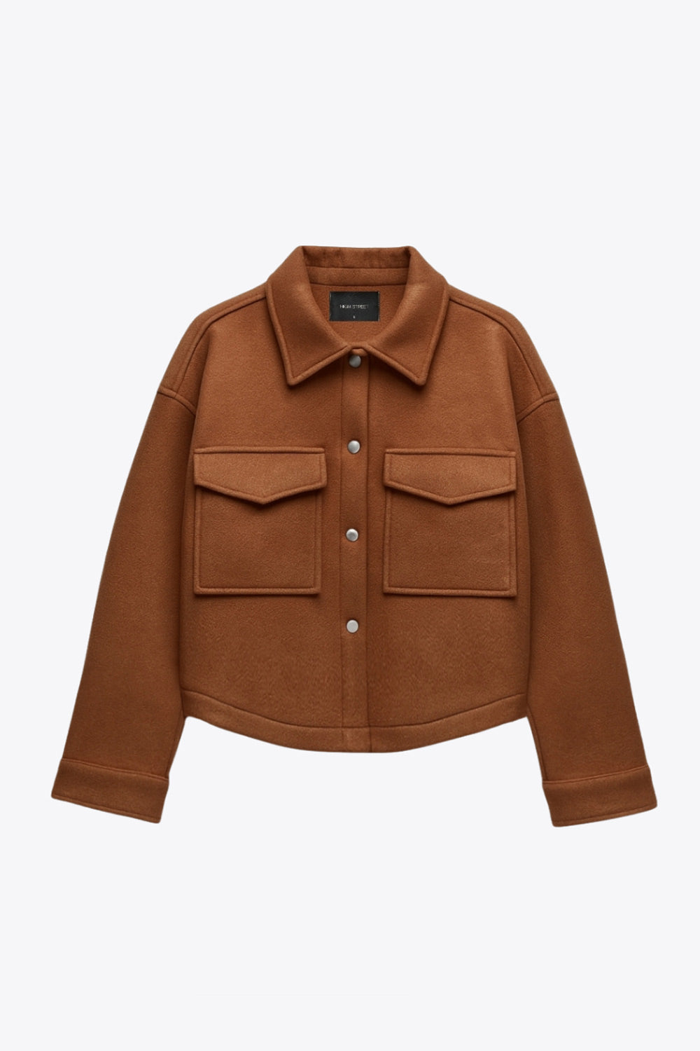 Chamarra corta de fit recto, cuello camisero, manga larga con puño abotonado, bolsillos delanteros con cartera, bajo curveado y cierre frontal con hilera de botones en contraste.