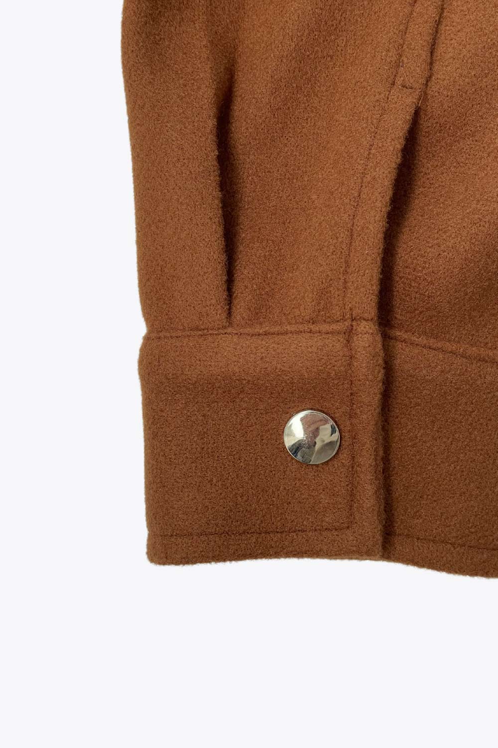 Chamarra corta de fit recto, cuello camisero, manga larga con puño abotonado, bolsillos delanteros con cartera, bajo curveado y cierre frontal con hilera de botones en contraste.