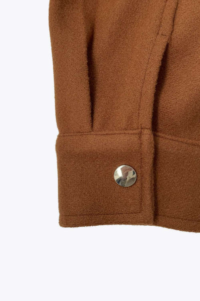 Chamarra corta de fit recto, cuello camisero, manga larga con puño abotonado, bolsillos delanteros con cartera, bajo curveado y cierre frontal con hilera de botones en contraste.