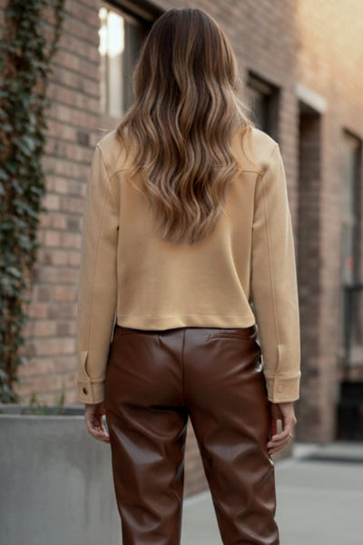 Chamarra corta de gamuza, fit recto, manga larga con puño abotonado, cuello camisero, bolsillos delanteros de parche con cartera y botones de presión. Cierre frontal con hilera de botones en contraste.