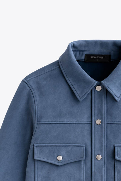 Chamarra corta de gamuza, fit recto, manga larga con puño abotonado, cuello camisero, bolsillos delanteros de parche con cartera y botones de presión. Cierre frontal con hilera de botones en contraste.