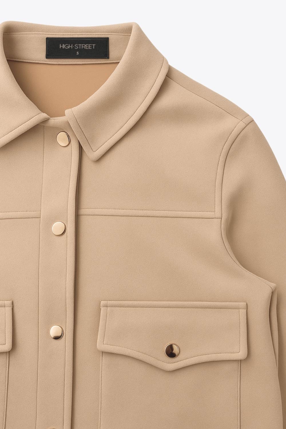 Chamarra corta de gamuza, fit recto, manga larga con puño abotonado, cuello camisero, bolsillos delanteros de parche con cartera y botones de presión. Cierre frontal con hilera de botones en contraste.