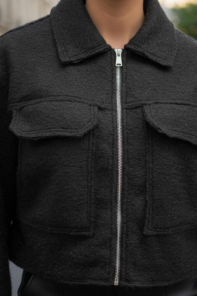 Chamarra corta de borreguillo, fit recto, manga larga con puño abotonado, cuello solapa, bolsillos frontales de parche con cartera y cierre frontal con cremallera visible en contraste.