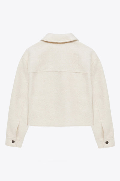 Chamarra corta de borreguillo, fit recto, manga larga con puño abotonado, cuello solapa, bolsillos frontales de parche con cartera y cierre frontal con cremallera visible en contraste.