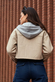 Chamarra corta de fit recto, manga larga con puño abotonado, cuello camisero, capucha en contraste, bolsillos delanteros de parche con cartera y cierre frontal con hilera de botones en contraste.