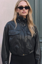 Chamarra de efecto piel, fit oversized, manga larga con puño abotonado, cuello alto, bolsillos delanteros con cartera, cortes decorativos y pretina elástica. Cierre frontal con cremallera oculta.