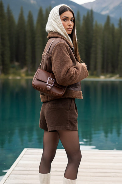 Chamarra corta de efecto piel, interior, mangas y cuello solapa de borreguillo, bolsillos delanteros de parche con detalle en contraste, fit recto, manga larga, costuras decorativas y cierre frontal con cremallera en contraste. Detalle de trabilla decorativa con hebilla en cuello.