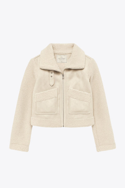 Chamarra corta de efecto piel, interior, mangas y cuello solapa de borreguillo, bolsillos delanteros de parche con detalle en contraste, fit recto, manga larga, costuras decorativas y cierre frontal con cremallera en contraste. Detalle de trabilla decorativa con hebilla en cuello.