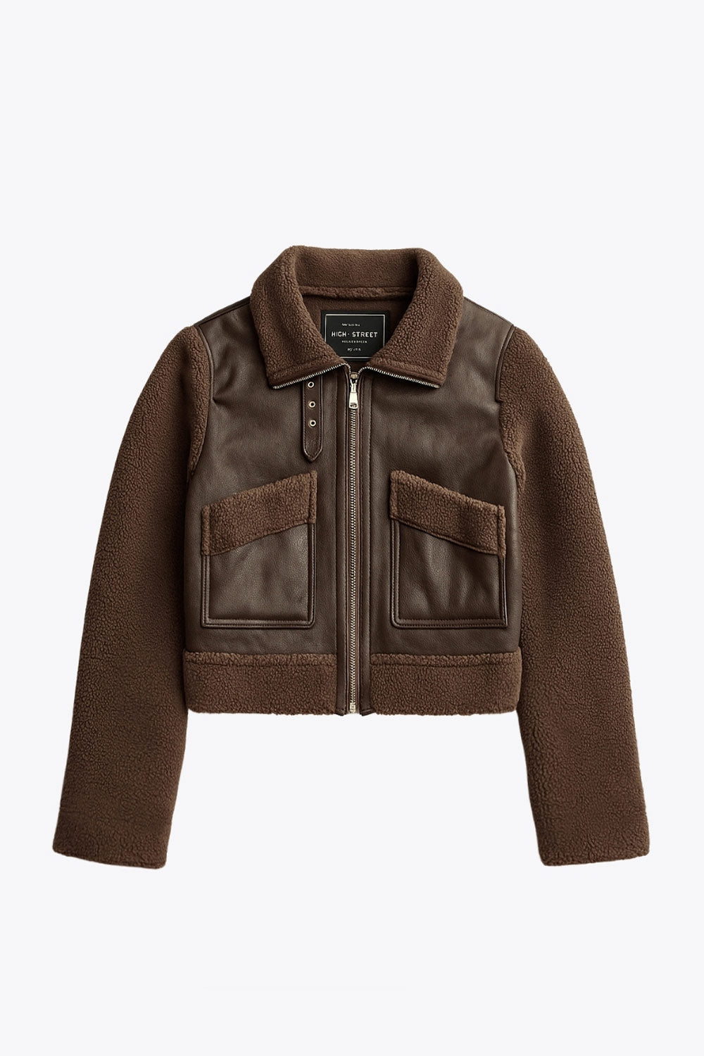 Chamarra corta de efecto piel, interior, mangas y cuello solapa de borreguillo, bolsillos delanteros de parche con detalle en contraste, fit recto, manga larga, costuras decorativas y cierre frontal con cremallera en contraste. Detalle de trabilla decorativa con hebilla en cuello.