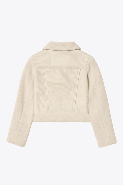 Chamarra corta de efecto piel, interior, mangas y cuello solapa de borreguillo, bolsillos delanteros de parche con detalle en contraste, fit recto, manga larga, costuras decorativas y cierre frontal con cremallera en contraste. Detalle de trabilla decorativa con hebilla en cuello.