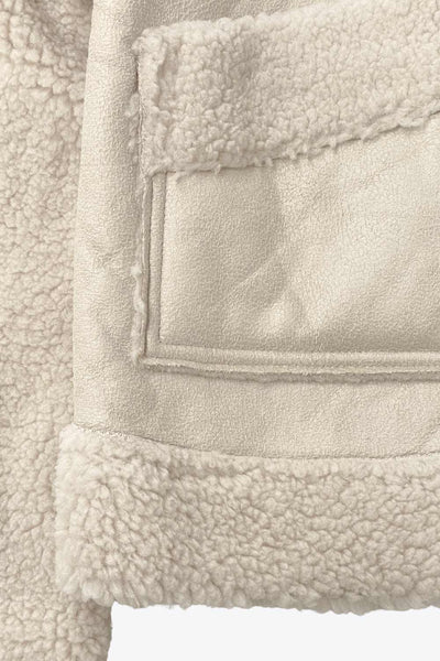 Chamarra corta de efecto piel, interior, mangas y cuello solapa de borreguillo, bolsillos delanteros de parche con detalle en contraste, fit recto, manga larga, costuras decorativas y cierre frontal con cremallera en contraste. Detalle de trabilla decorativa con hebilla en cuello.