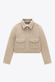 Chamarra corta de fit recto, manga larga con puño abotonado, cuello camisero, bolsillos delanteros de parche con cartera y cierre frontal con cremallera visible en contraste.