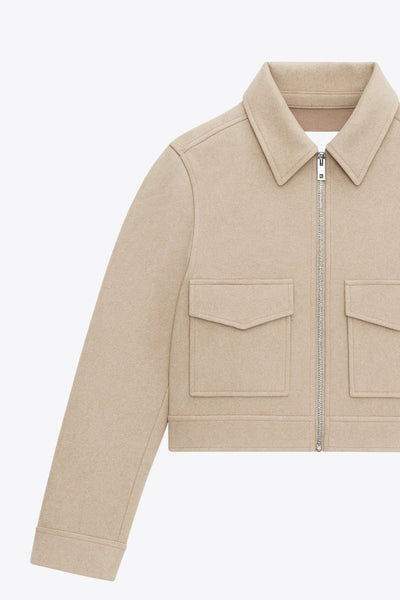 Chamarra corta de fit recto, manga larga con puño abotonado, cuello camisero, bolsillos delanteros de parche con cartera y cierre frontal con cremallera visible en contraste.