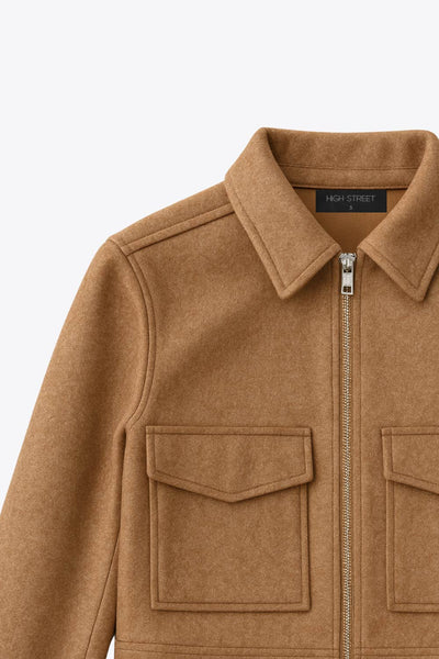 Chamarra corta de fit recto, manga larga con puño abotonado, cuello camisero, bolsillos delanteros de parche con cartera y cierre frontal con cremallera visible en contraste.