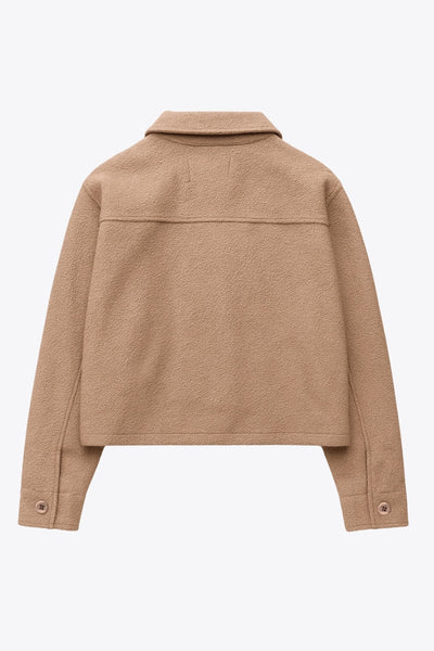 Chamarra corta de borreguillo, manga larga con puño abotonado, cuello solapa, bolsillos frontales de parche con cartera y botón. Cierre frontal con hilera de botones.