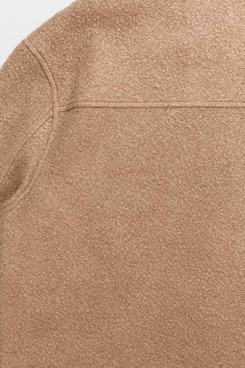 Chamarra corta de borreguillo, manga larga con puño abotonado, cuello solapa, bolsillos frontales de parche con cartera y botón. Cierre frontal con hilera de botones.