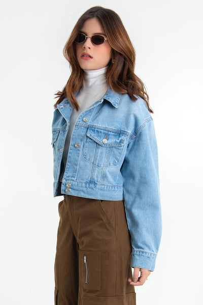 Chamarra corta de denim, fit ligeramente oversized, manga larga con puño abotonado, cuello clásico, bolsillos frontales con cartera y botón en contraste. Cierre frontal con hilera de botones en contraste.
