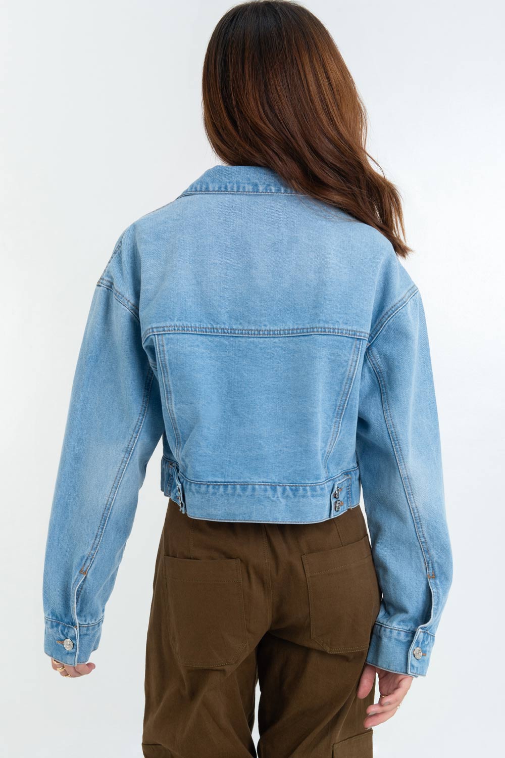 Chamarra corta de denim, fit ligeramente oversized, manga larga con puño abotonado, cuello clásico, bolsillos frontales con cartera y botón en contraste. Cierre frontal con hilera de botones en contraste.
