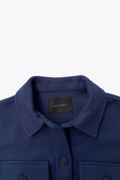 Chamarra corta de fit recto, cuello camisero, manga larga con puño abotonado, bolsillos delanteros de parche con cartera y botón en contraste. Cierre frontal con hilera de botones en contraste.