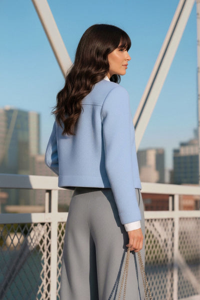 Chamarra corta de fit recto, cuello camisero, manga larga con puño abotonado, cortes decorativos frontales, bolsillos delanteros con cartera y botón. Cierre frontal con hilera de botones en contraste.