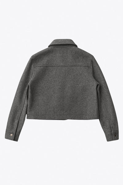 Chamarra corta de fit recto, cuello camisero, manga larga con puño abotonado, cortes decorativos frontales, bolsillos delanteros con cartera y botón. Cierre frontal con hilera de botones en contraste.