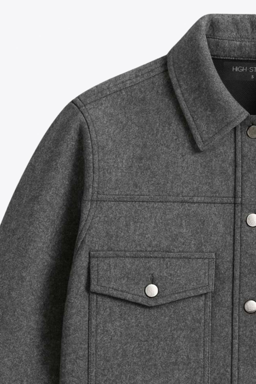 Chamarra corta de fit recto, cuello camisero, manga larga con puño abotonado, cortes decorativos frontales, bolsillos delanteros con cartera y botón. Cierre frontal con hilera de botones en contraste.