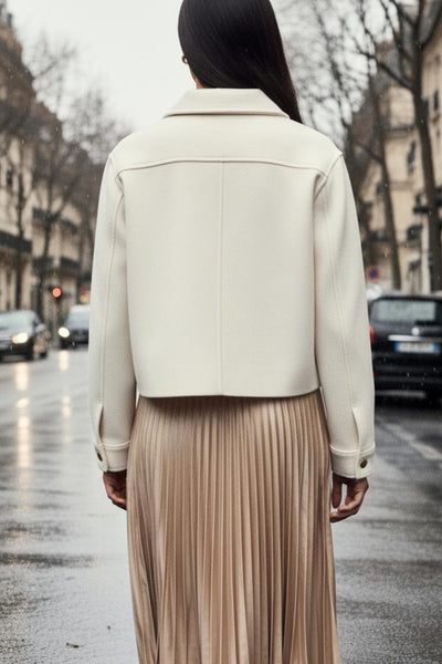 Chamarra corta de fit recto, cuello camisero, manga larga con puño abotonado, bolsillos delanteros con cartera y botón. Cierre frontal con hilera de botones en contraste.