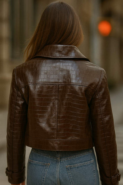 Chamarra corta de efecto piel, textura animal, cuello solapa, bolsillos delanteros decorativos con cartera, fit recto, manga larga con trabilla y botón en puños. Cierre frontal con hilera de botones y detalle de pretina en cintura.