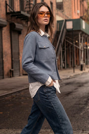 Blazer corto de cuello redondo, bolsillos decorativos con solapa y botón en contraste, fit recto, manga larga y cierre frontal con hilera de botones en contraste.