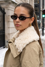 Chamarra corta de manga larga con puño, cuello solapa en contraste con borreguillo, bolsillos delanteros con cremallera y elástico con plisados en bajo. Cierre frontal con cremallera oculta.