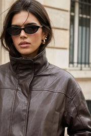 Chamarra de efecto piel, fit oversized, manga larga con puño abotonado, cuello alto, bolsillos delanteros con vivos, cortes decorativos y elástico en bajo. Cierre frontal con cremallera oculta.