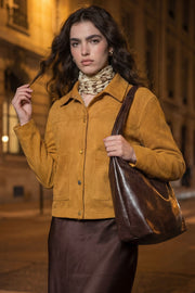 Chamarra corta de gamuza, fit recto, manga larga, cuello camisero, bolsillos delanteros de parche y cierre frontal con hilera de botones en contraste.