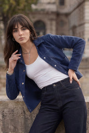 Chamarra corta de gamuza, fit recto, manga larga, cuello camisero, bolsillos delanteros de parche y cierre frontal con hilera de botones en contraste.