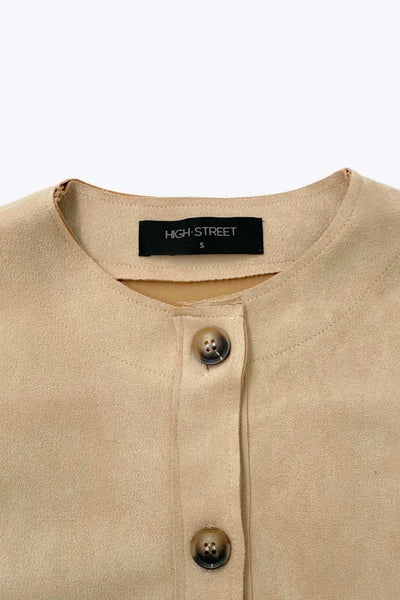 Blazer corto de gamuza, cuello redondo, bolsillos frontales con solapa y botón en contraste, fit recto, manga larga y cierre frontal con hilera de botones en contraste.