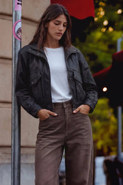Chamarra de efecto piel, fit oversized, manga larga con puño abotonado, cuello alto, bolsillos delanteros con vivos y carteras, cortes decorativos y pretina elástica. Cierre frontal con cremallera oculta.