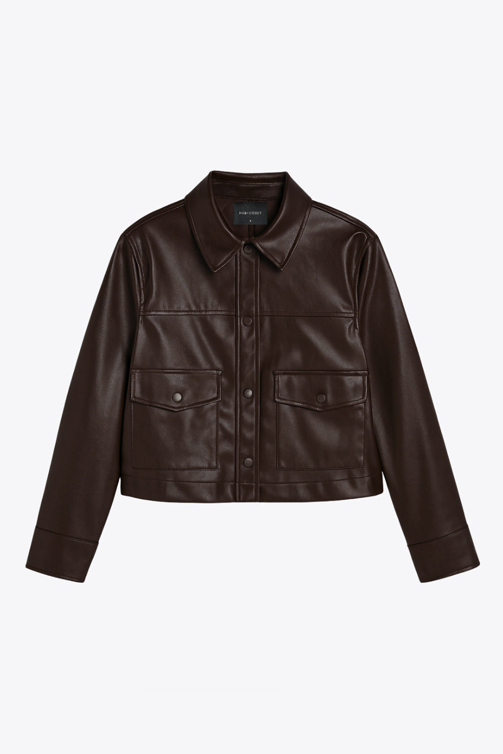 Chamarra corta de efecto piel, fit recto, cuello camisero, manga larga con puño abotonado, bolsillos delanteros de parche con cartera y botón. Cierre frontal con hilera de botones.