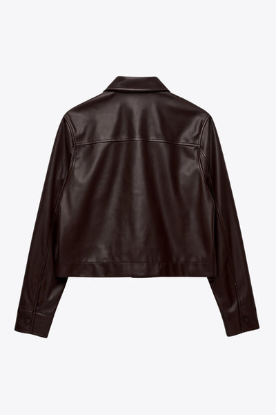 Chamarra corta de efecto piel, fit recto, cuello camisero, manga larga con puño abotonado, bolsillos delanteros de parche con cartera y botón. Cierre frontal con hilera de botones.