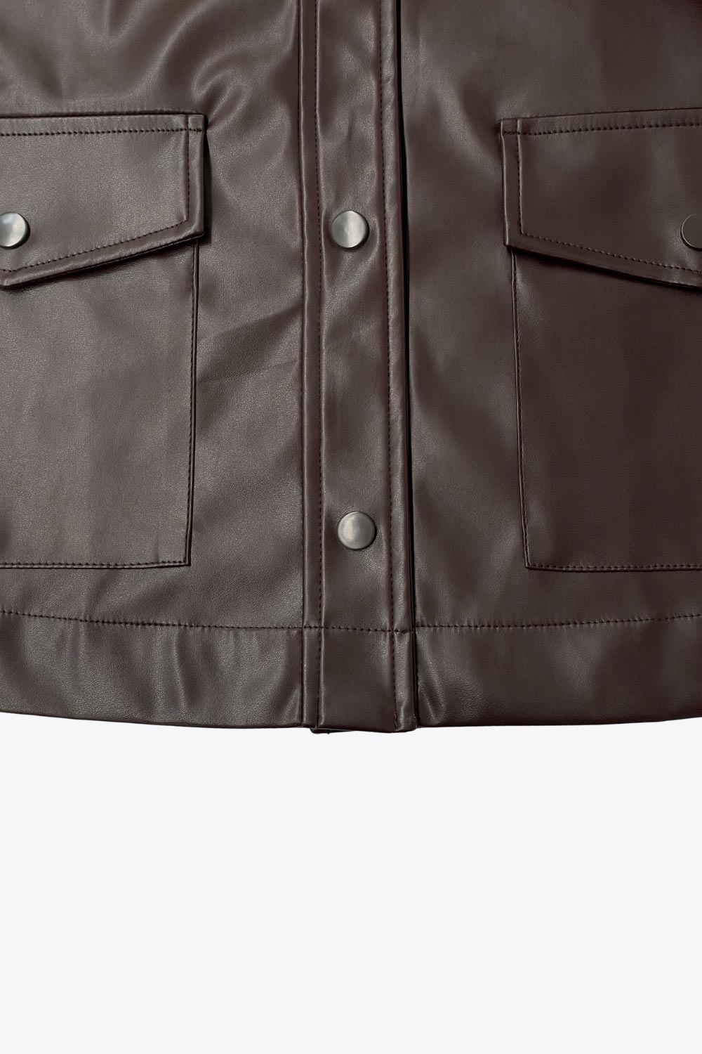 Chamarra corta de efecto piel, fit recto, cuello camisero, manga larga con puño abotonado, bolsillos delanteros de parche con cartera y botón. Cierre frontal con hilera de botones.