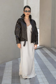 Chamarra cruzada de efecto piel, fit oversized, manga larga con puño abotonado, con cuello alto , trabillas con botones en hombros, cortes decorativos, bolsillos delanteros, pretina elástica con hebilla frontal en contraste. Cierre frontal con cremallera.