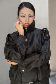 Chamarra cruzada de efecto piel, fit oversized, manga larga con puño abotonado, con cuello alto , trabillas con botones en hombros, cortes decorativos, bolsillos delanteros, pretina elástica con hebilla frontal en contraste. Cierre frontal con cremallera.