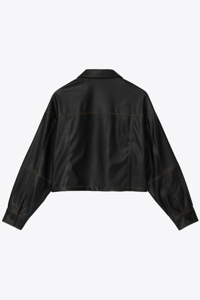 Chamarra corta de efecto piel, fit recto, cuello camisero, manga larga con puño abotonado, bolsillos delanteros de parche y cierre frontal con hilera de botones de presión. Detalle de costuras decorativas en contraste.