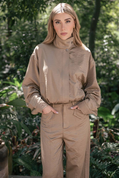 Chamarra de fit fluido, manga larga abullonada con puños abotonados, cuello alto con botón y cierre frontal con cremallera oculta.