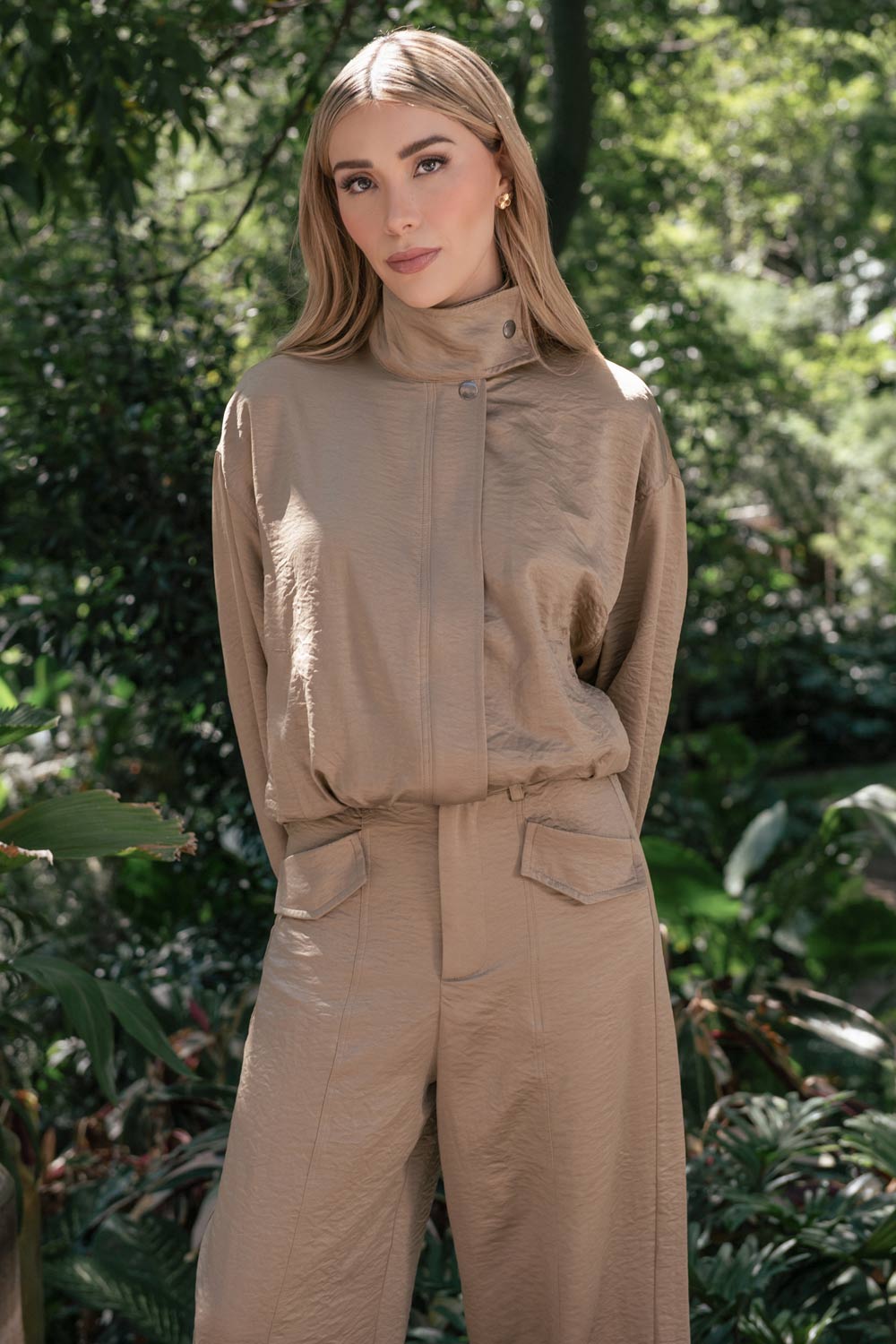 Chamarra de fit fluido, manga larga abullonada con puños abotonados, cuello alto con botón y cierre frontal con cremallera oculta.