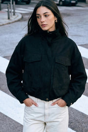 Chamarra de fit oversized, manga larga con puño abotonado, cuello alto, bolsillos delanteros de parche con cartera, cortes decorativos y pretina elástica. Cierre frontal con cremallera oculta y botones en contraste. Detalle de rib elástico en bajo.