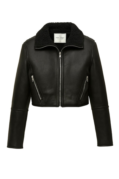 Chamarra corta de efecto piel, interior de borreguillo, cuello solapa, bolsillos delanteros con cremalleras, fit recto, manga larga con costuras decorativas y cierre frontal con cremallera en contraste.