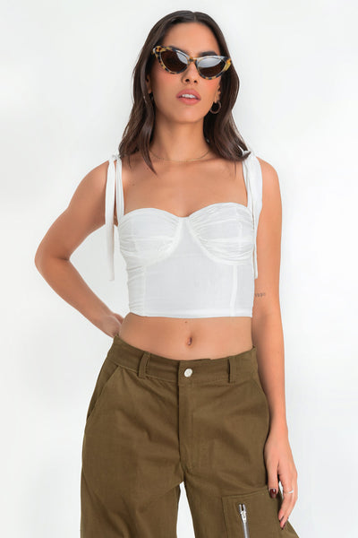 Crop top de fit ajustado, escote corazón con cortes decorativos y detalles plisados, costuras frontales y tirantes con nudo amarrable. Fruncido en espalda y cierre posterior con cremallera visible en contraste.